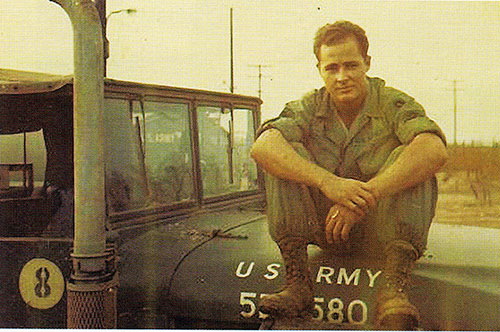 SGT Seay sitting on the hood of his truck in Viet Nam. 