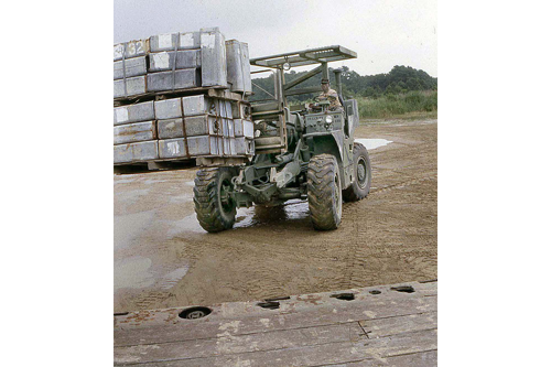 Rough Terrain Forklift in the process of loading a pallet on to semitrailer.